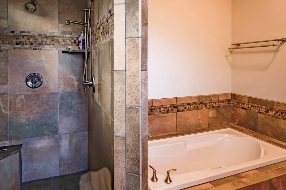A modern bathroom with both a walk-in shower and a bathtub, featuring elegant tile detailing. The space feels clean, tranquil, and luxurious, evoking spa-like relaxation.