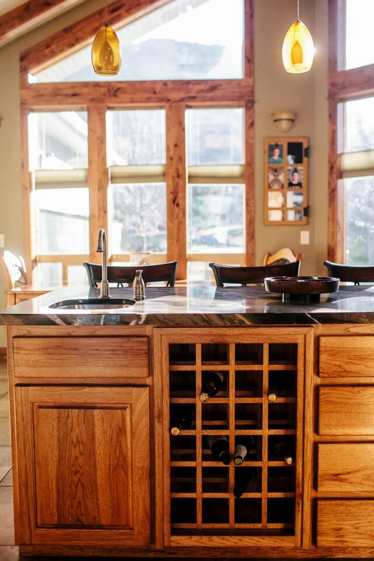 This image displays a warm kitchen setting with a prominent island and a built-in wine rack, complemented by large windows that allow natural light to flood the space. The kitchen is designed for both practicality and hosting, with plenty of space for meal prep, entertaining guests, or enjoying family time.