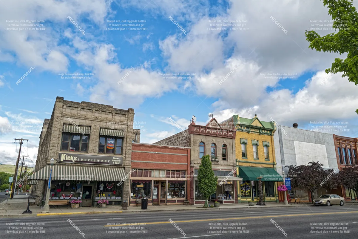 A lively downtown street scene with the Kicks sportswear store and colorful, charming buildings lining the street. Trees add appeal, and the area invites strolling, shopping, and outdoor dining.
