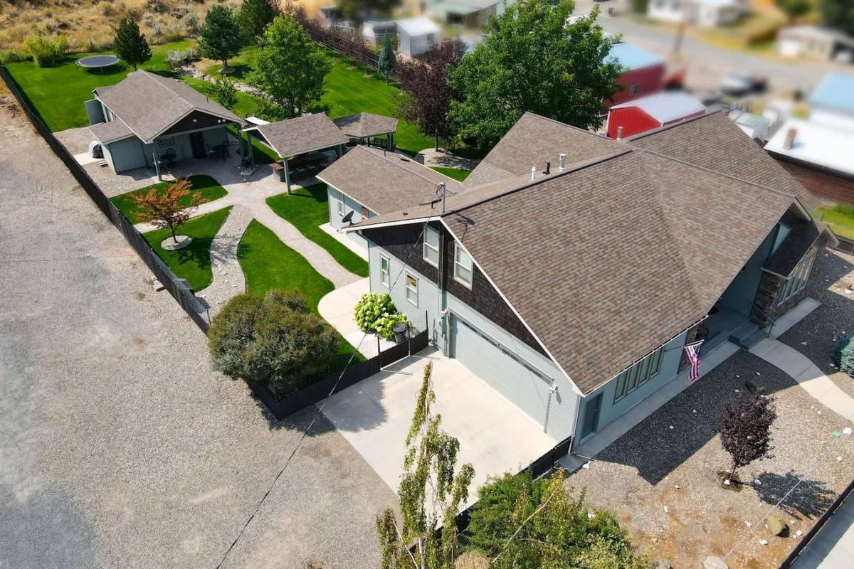 The hero image showcases the grand main house of the Wunder Mine Estate, nestled amid lush greenery with inviting outdoor pathways leading to a separate guest house. The expansive backyard is bathed in the warm glow of sunset, hinting at serene evenings and festive gatherings under the Oregon sky.