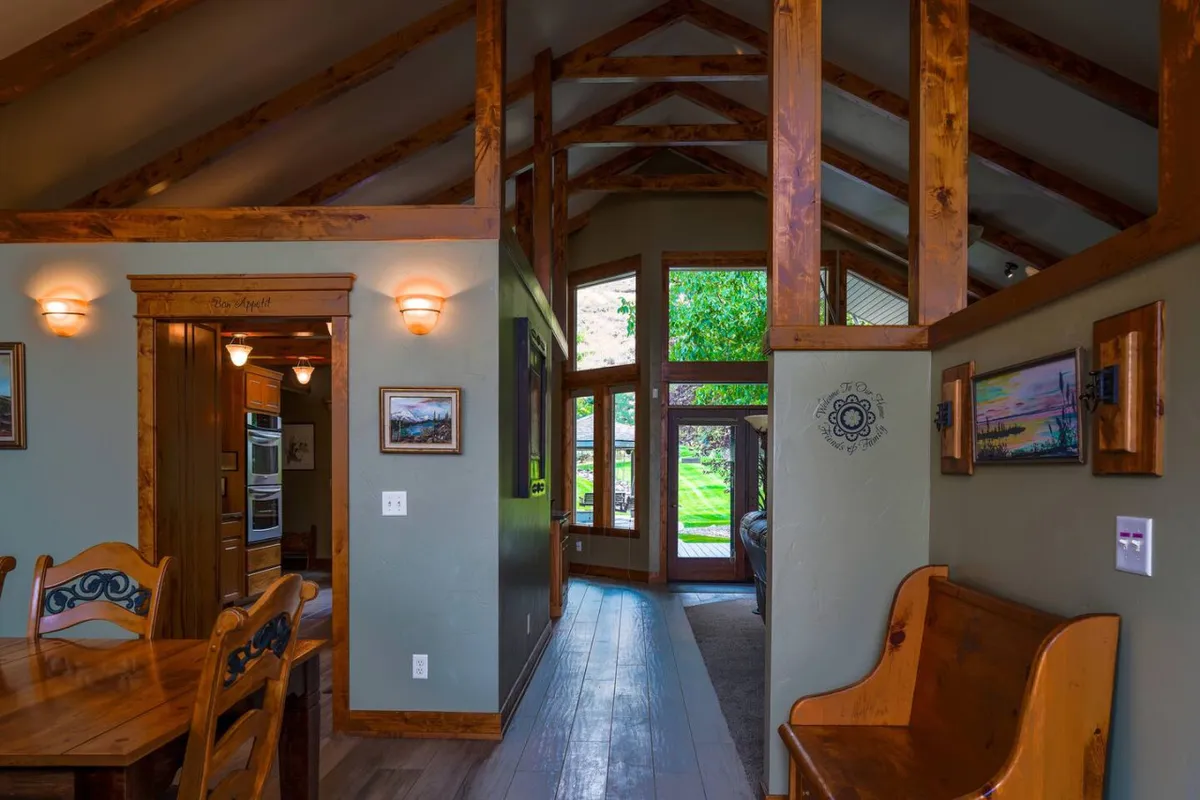 A cozy dining area featuring a wooden dining table, bench seating, exposed wood beams, and large windows that let in abundant daylight. The ambiance is intimate and inviting, ideal for family gatherings or quiet moments with loved ones.