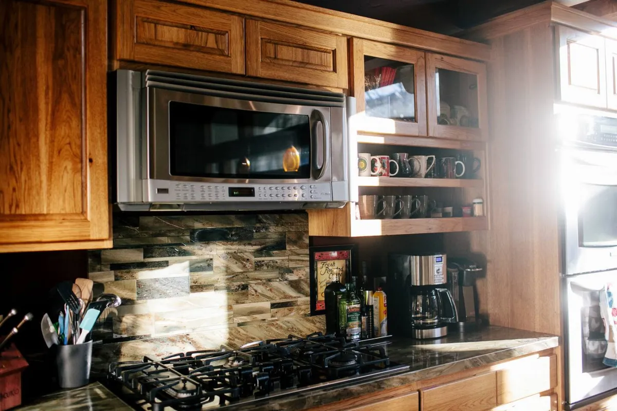 This cozy kitchen scene features a gas stove, microwave, coffee maker, and kitchen cabinets, conveying an active space where family breakfast, holiday dinners, or baking cookies together can easily take place. The layout fosters a sense of warmth and everyday activity.